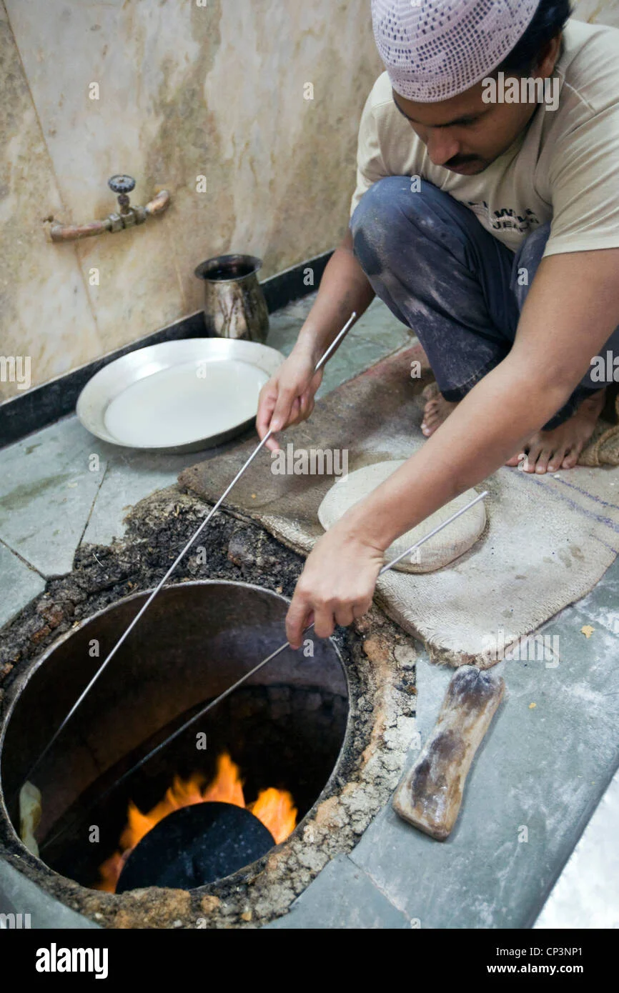 l-m-rahman-preparing-and-cooking-fresh-naan-bread-in-the-tandoor-oven-CP3NP1.webp