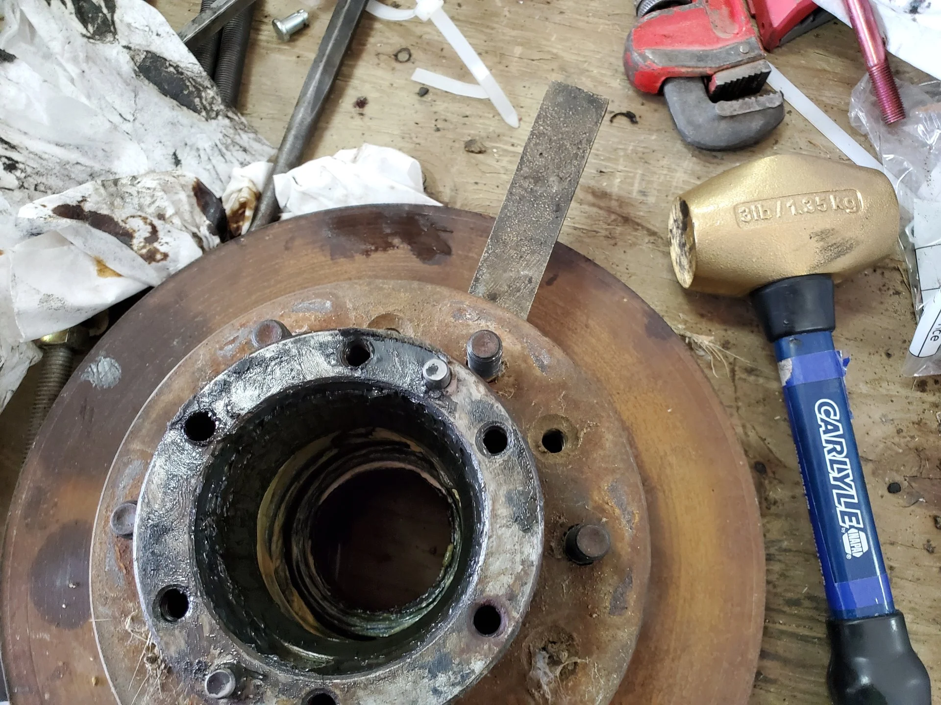 USING A BRASS WEDGE AND HAMMER TO SEPERATE THE ROTOR FROM THE WHEEL HUB.webp